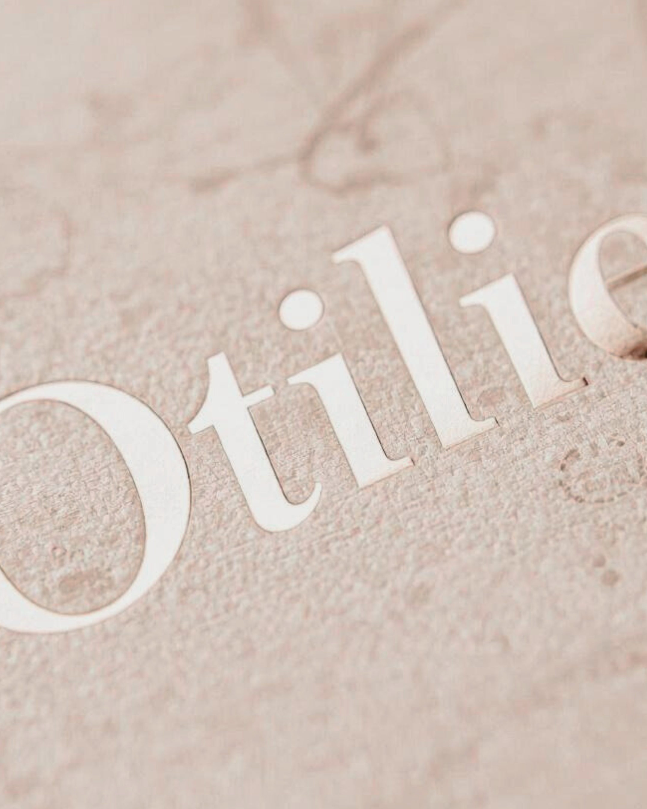 Close-up of the word 'detail' engraved in a textured, pinkish surface, possibly a metallic or stone material.