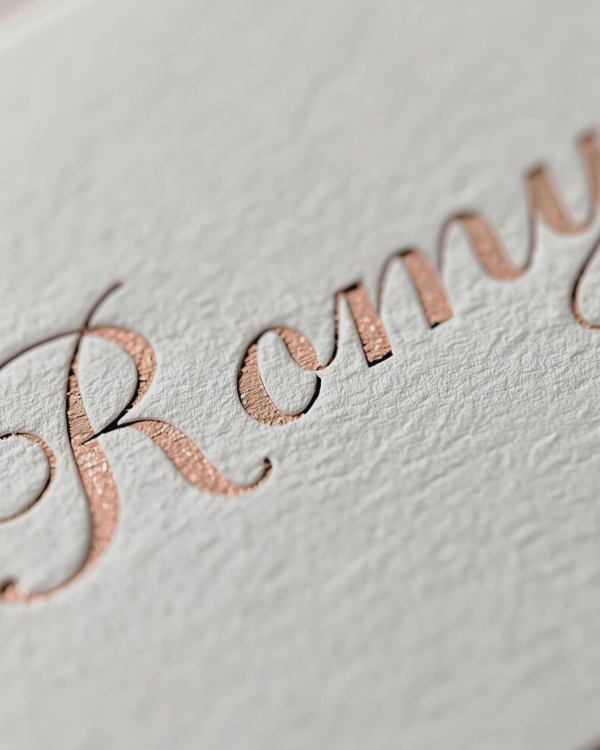 Close-up of the word "CREAM" embossed in rose gold on textured white paper.
