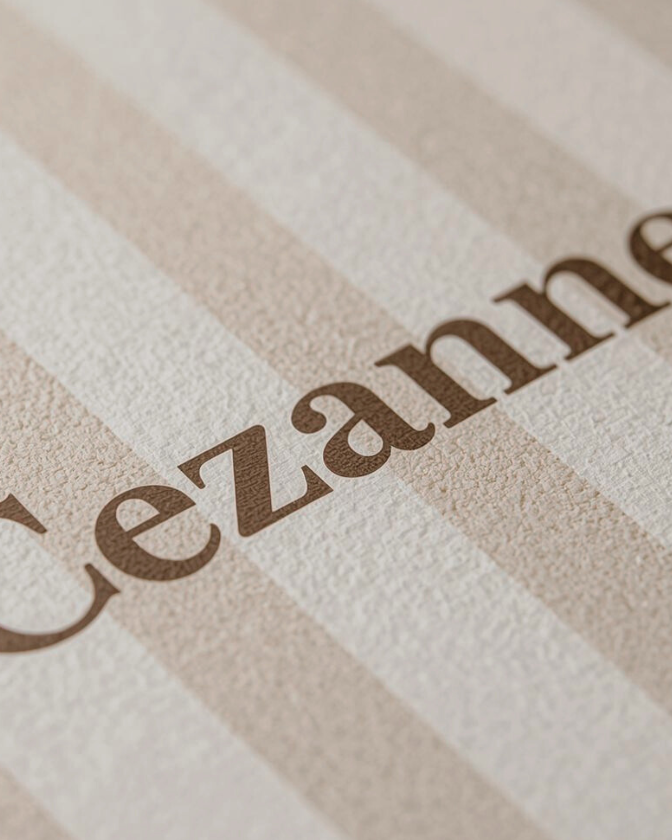 Close-up of the word 'Cezary' printed on textured paper with beige and cream striped background.