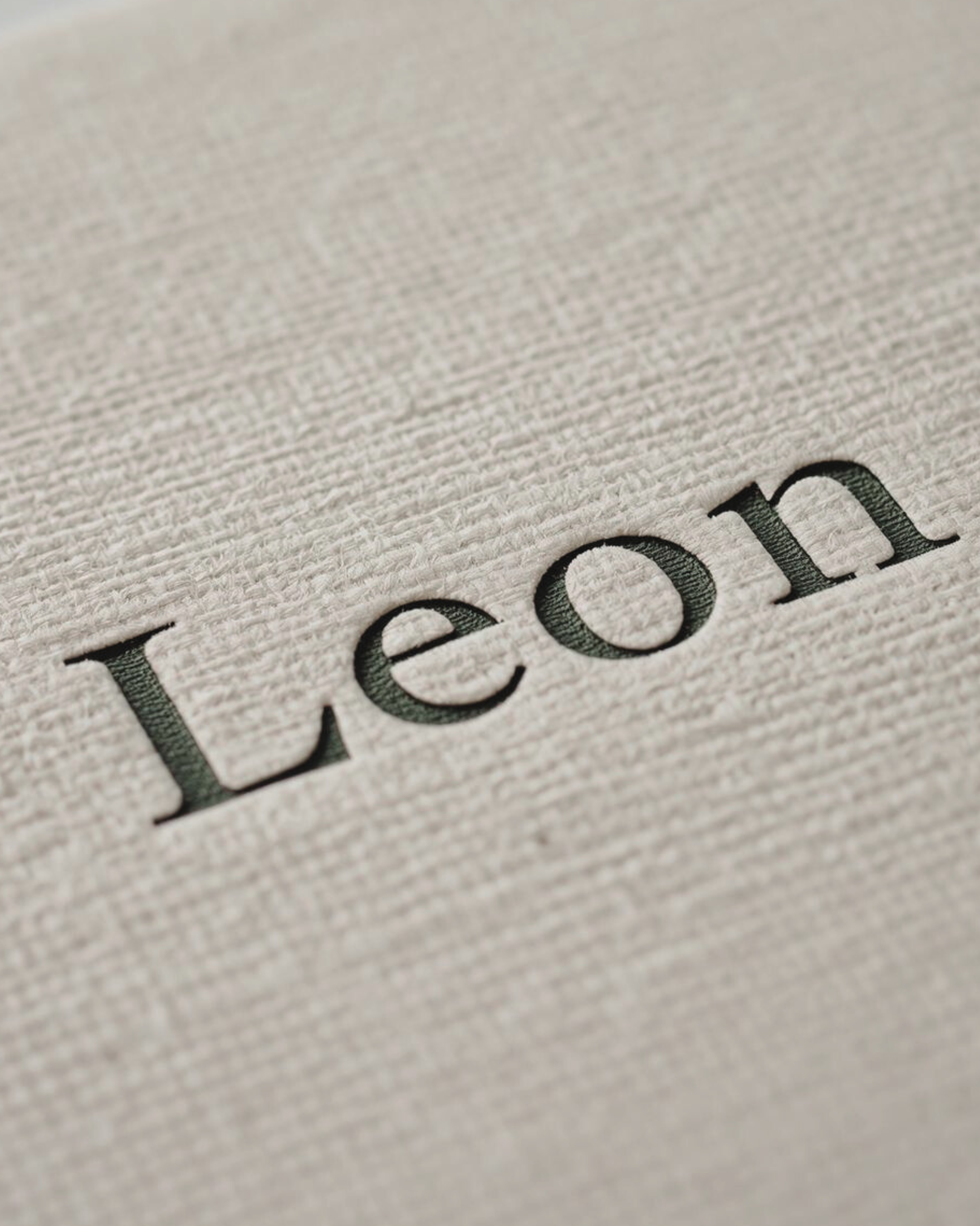 Close-up of the word 'Leona' printed in black on textured white paper.