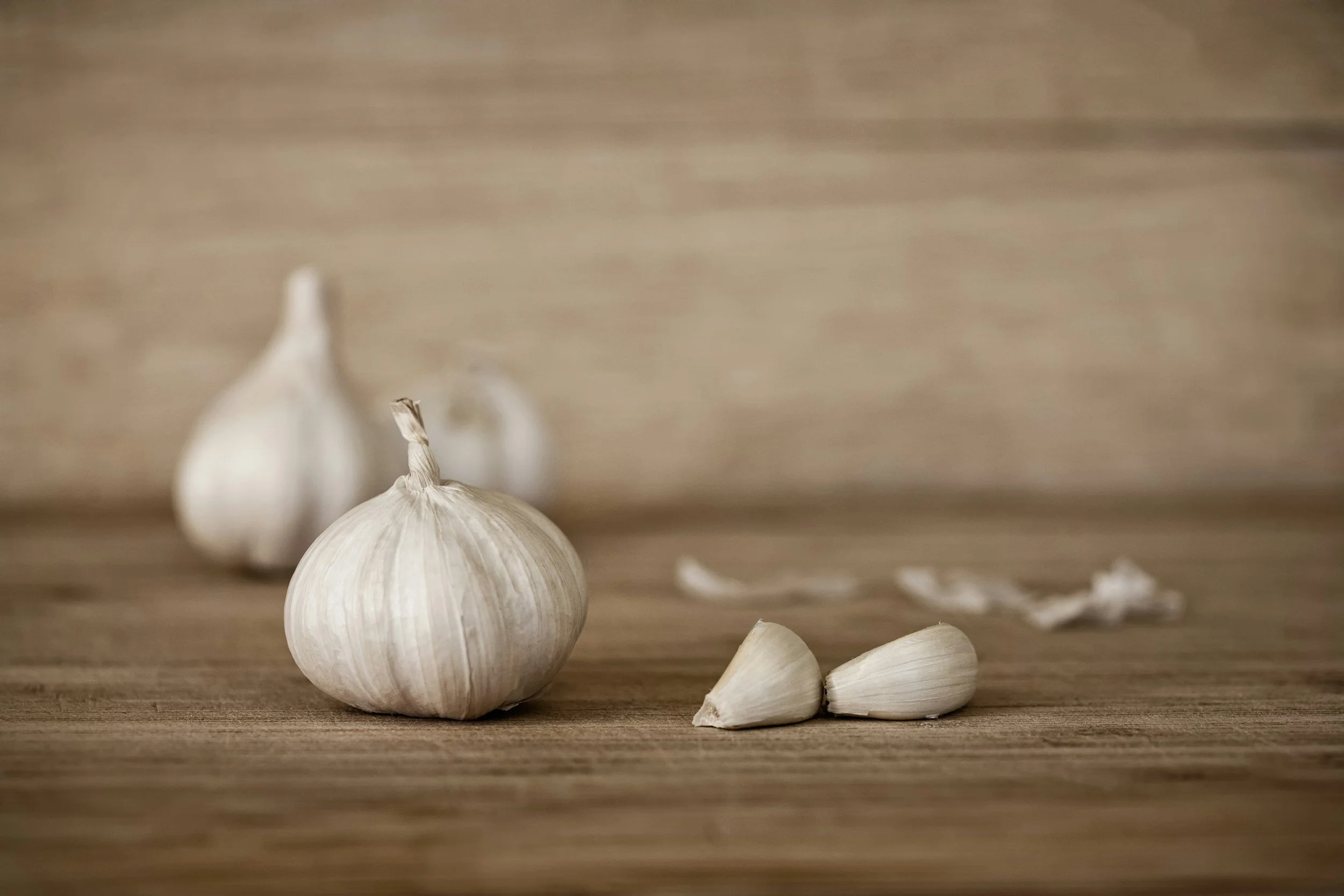 Cloves of garlic on a wooden surface with a blurred wooden background.