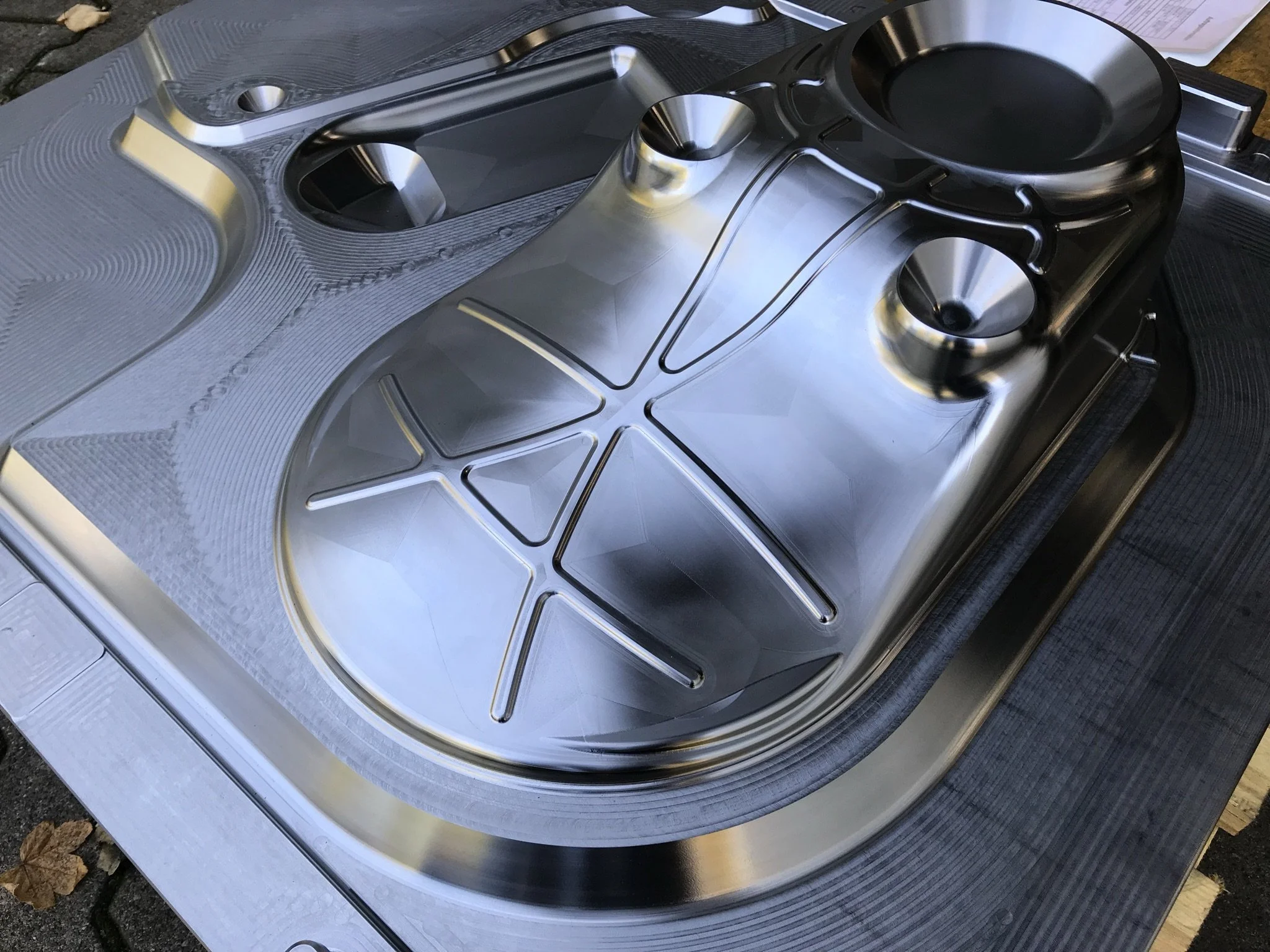 Ein großer, runder, glänzender Metallbehälter mit Abteilungen, wahrscheinlich für die Herstellung von Speiseeis, auf einer Arbeitsfläche.