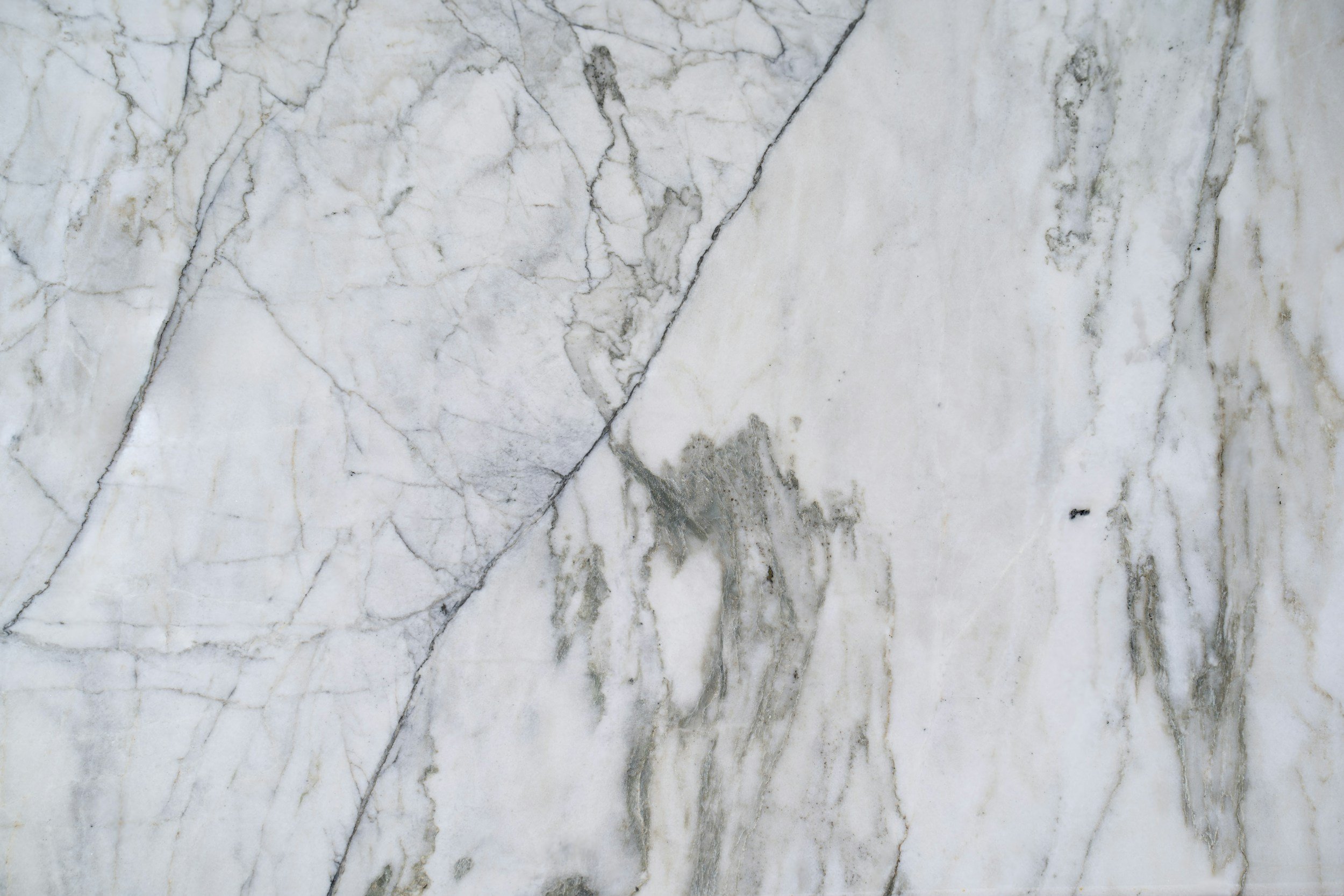 Close-up of a white marble surface with gray veining and natural patterns.