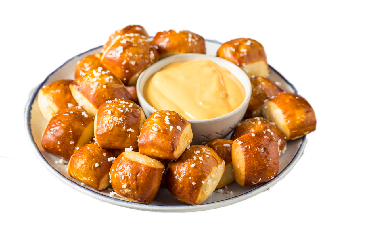 Plate of soft pretzel bites with coarse salt with a cup of cheese sauce in the center.