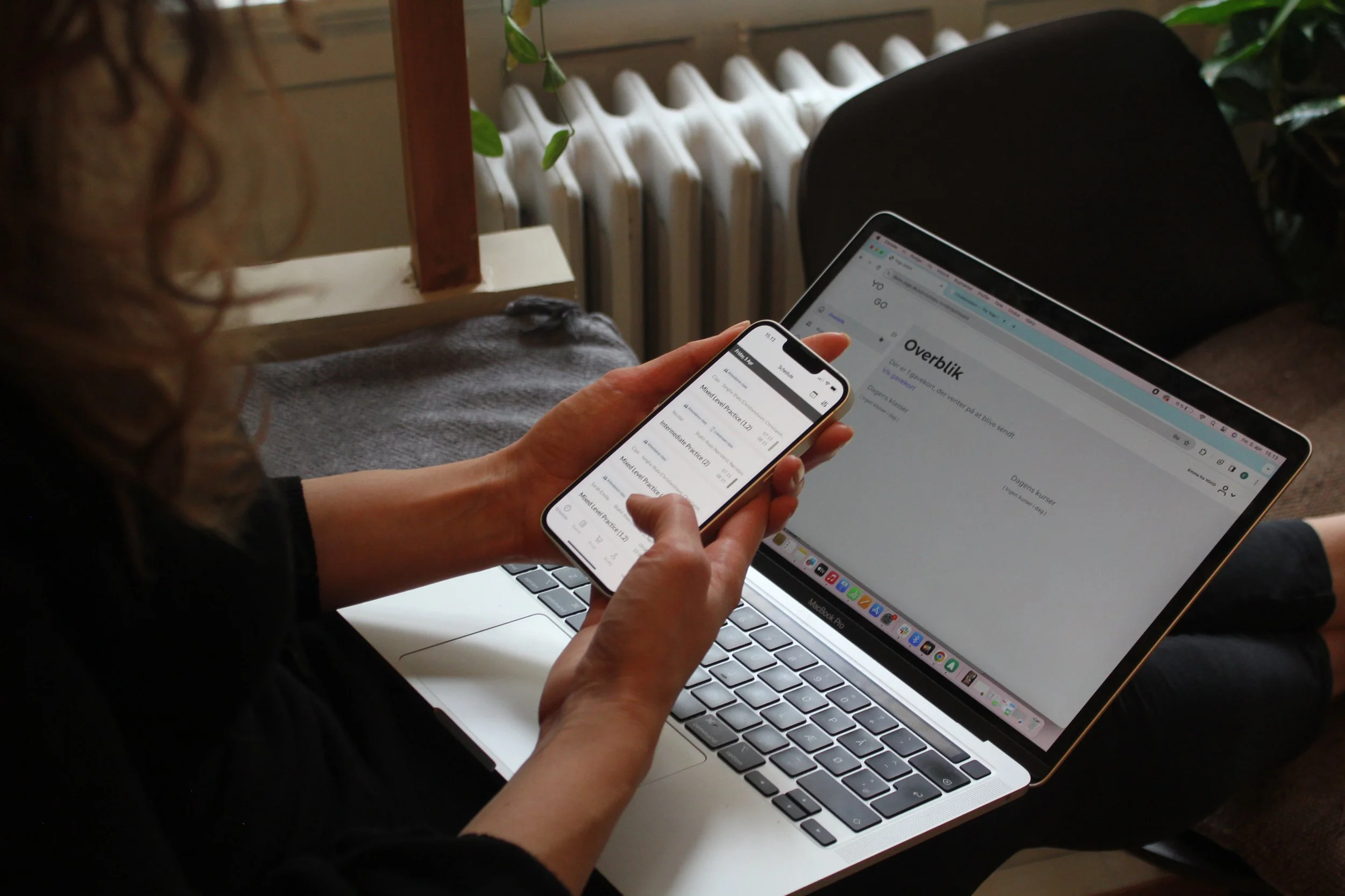 Person holding a smartphone in front of a computer