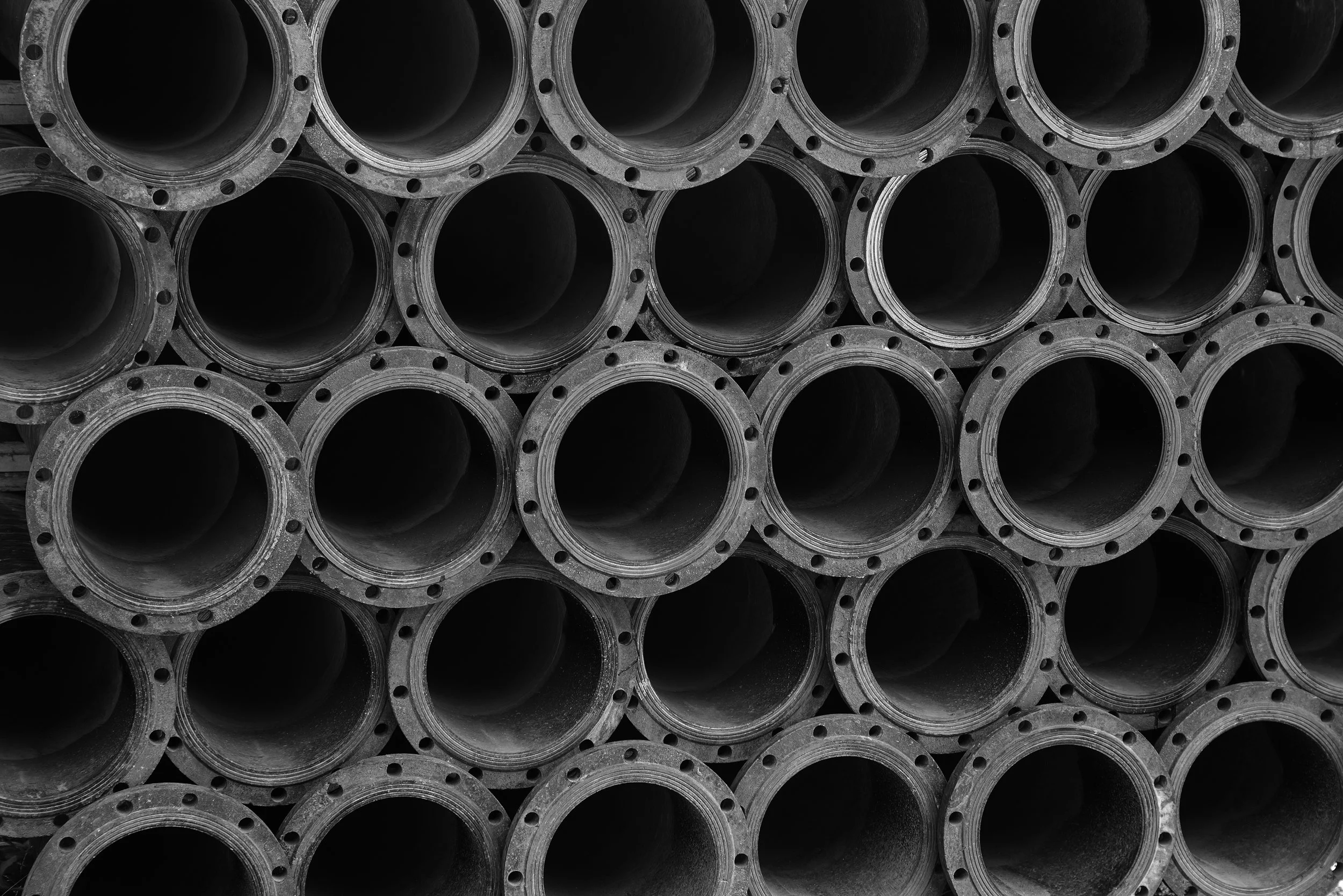 Stacked black metal pipes with flanged ends