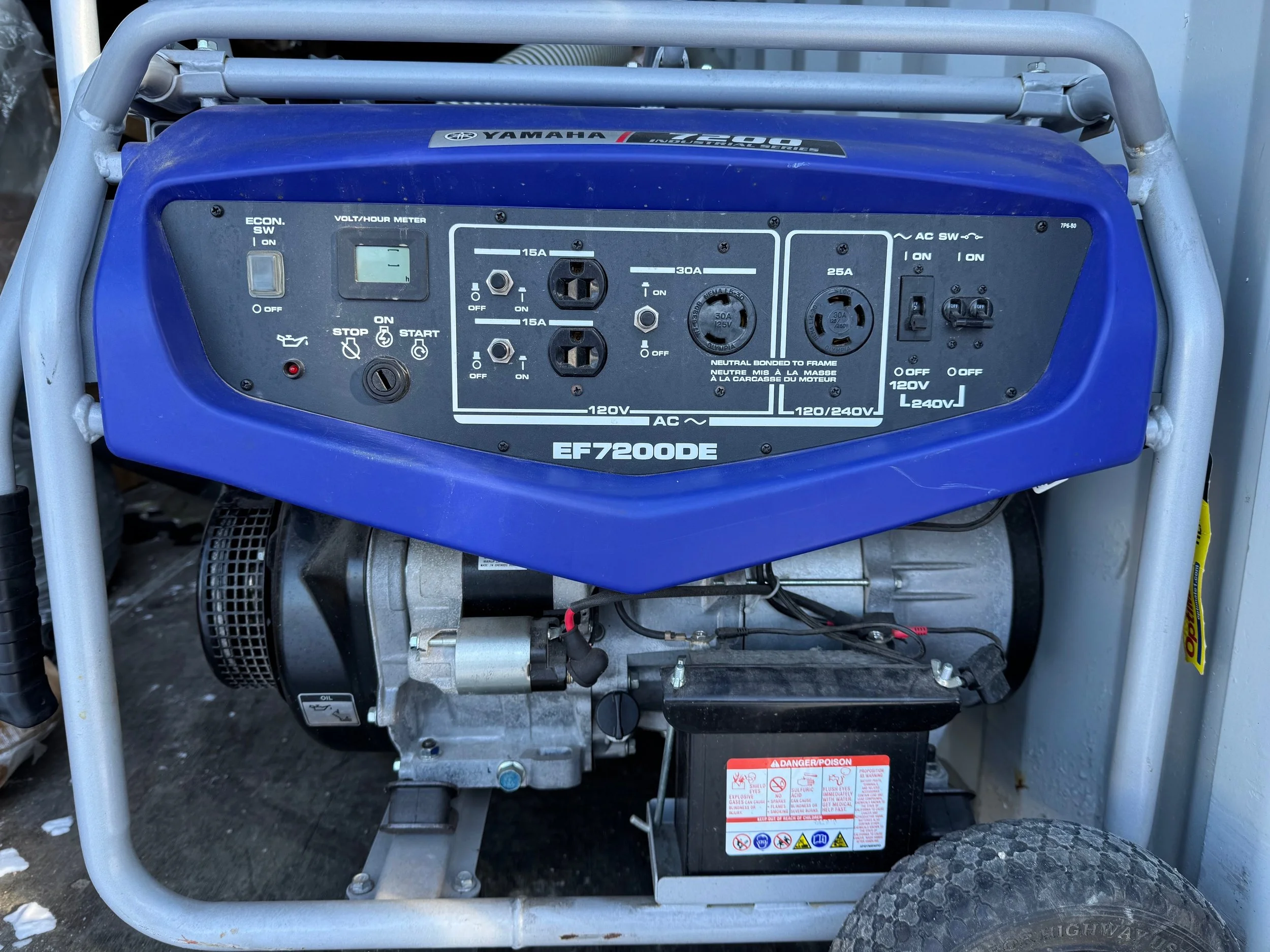 A landscape with mountains in the background, partially snow-capped, and a small modern building on a grassy hill in the foreground.