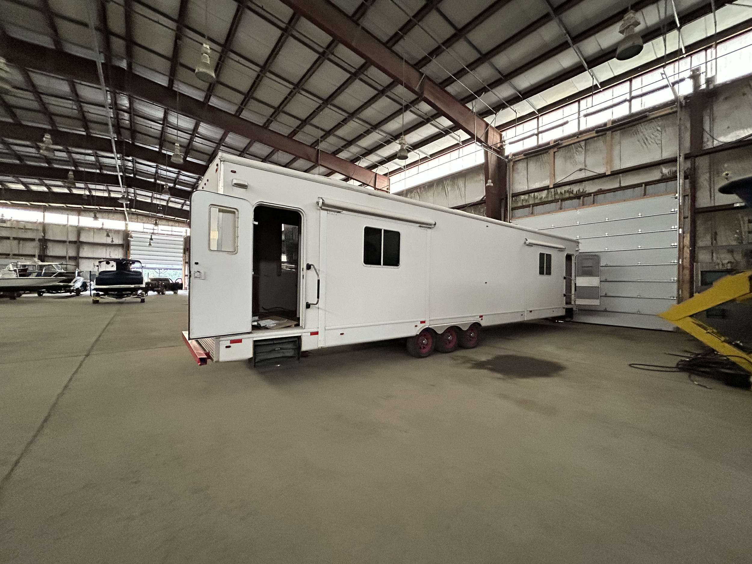 A house on green rolling hills with snow-capped mountains in the background under cloudy sky.