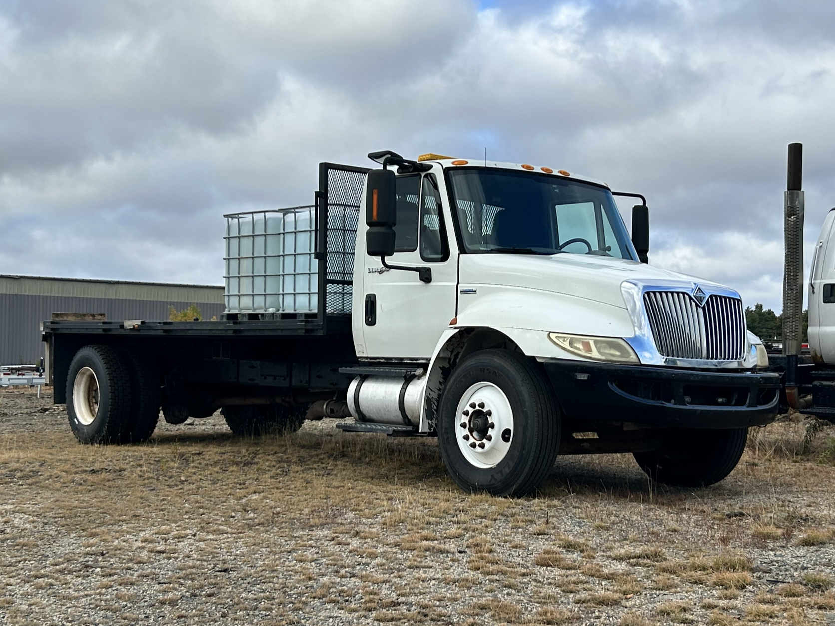 Scenic view of a house on a hillside with a snow-capped mountain range in the background under a cloudy sky.