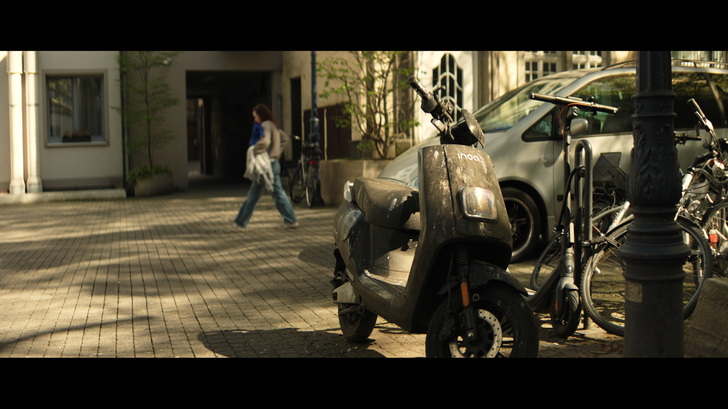 Parkender Roller in ruhiger Straße mit Person im Hintergrund im anamorphischen Look – aufgenommen mit Blazar Mantis 50mm