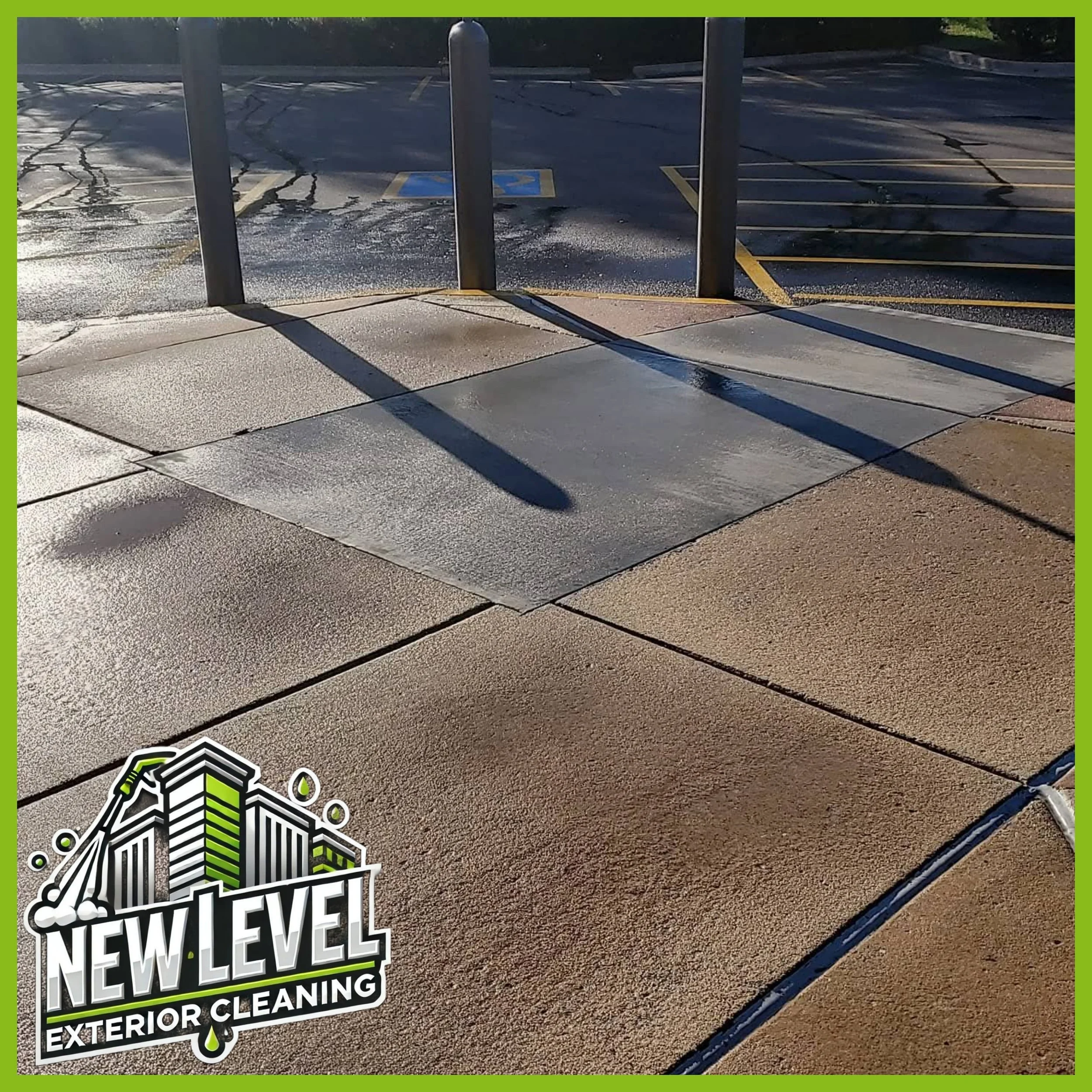 Cleaned sidewalk and wheel stop in a parking lot with shadows and wet surface, with a business logo for New Level Exterior Cleaning in the corner.