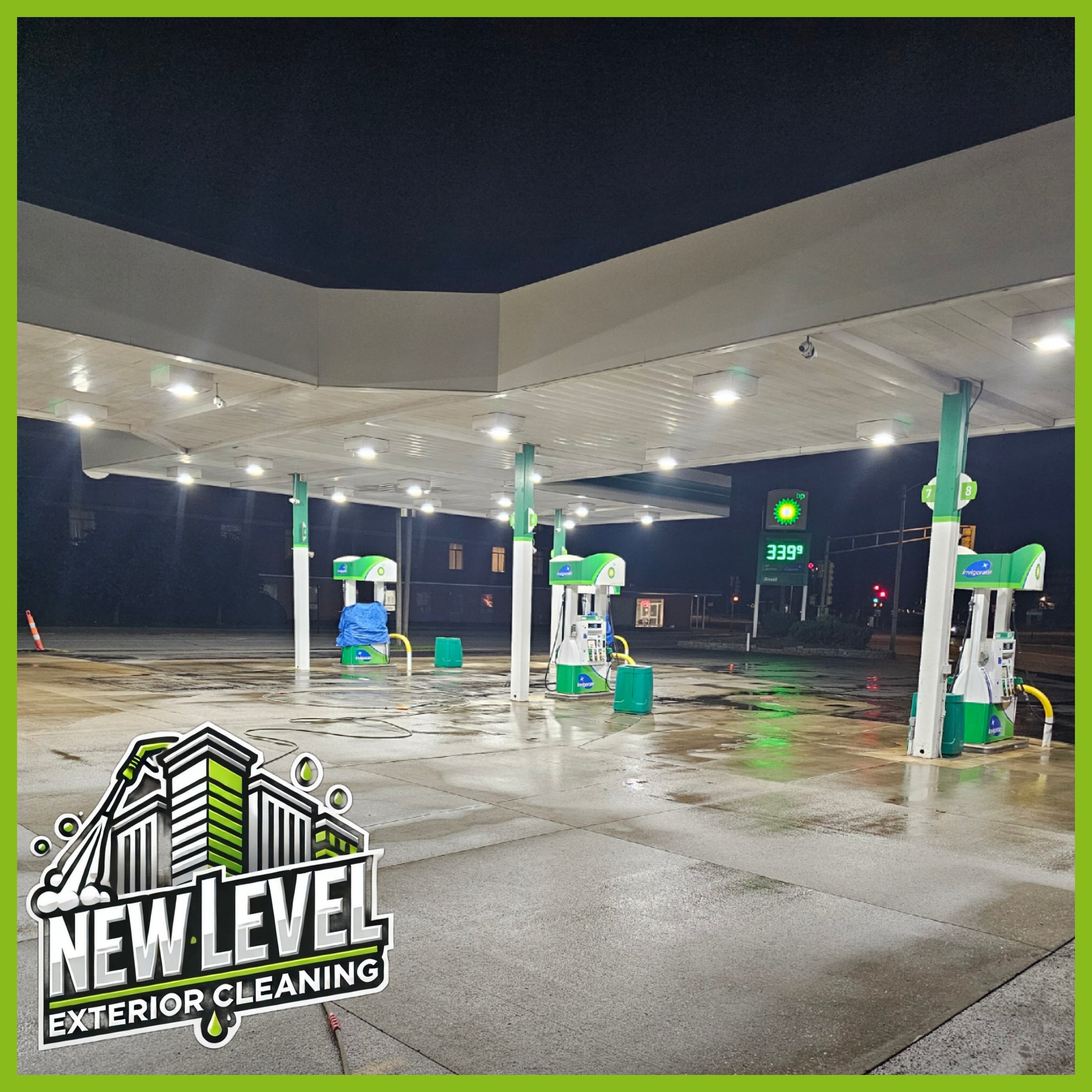 Empty gas station at night with wet pavement, illuminated pumps, and a digital price sign showing $3.39 per gallon.