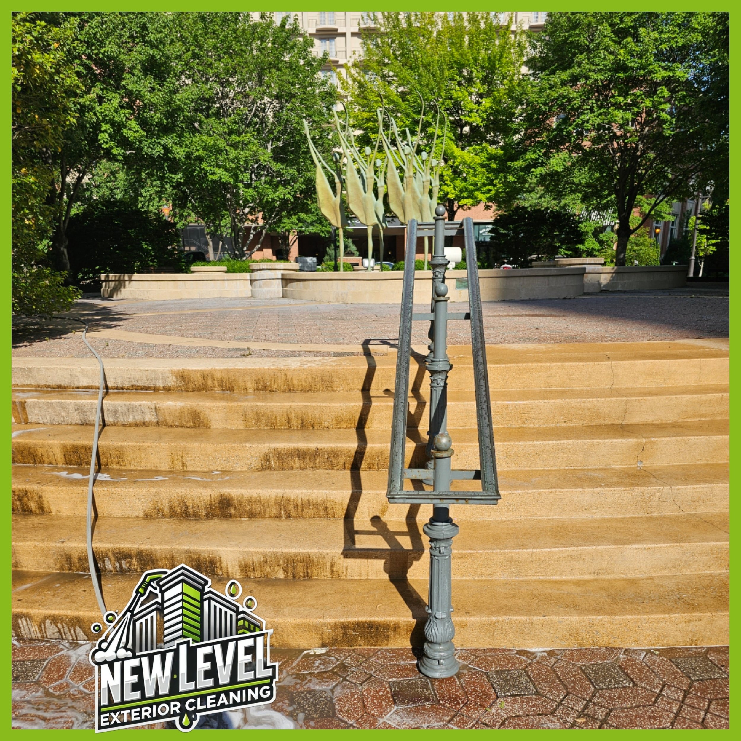 Set of outdoor steps next to a decorative railing, with trees and a sculpture in the background, and a logo for New Level Exterior Cleaning in the bottom left corner.