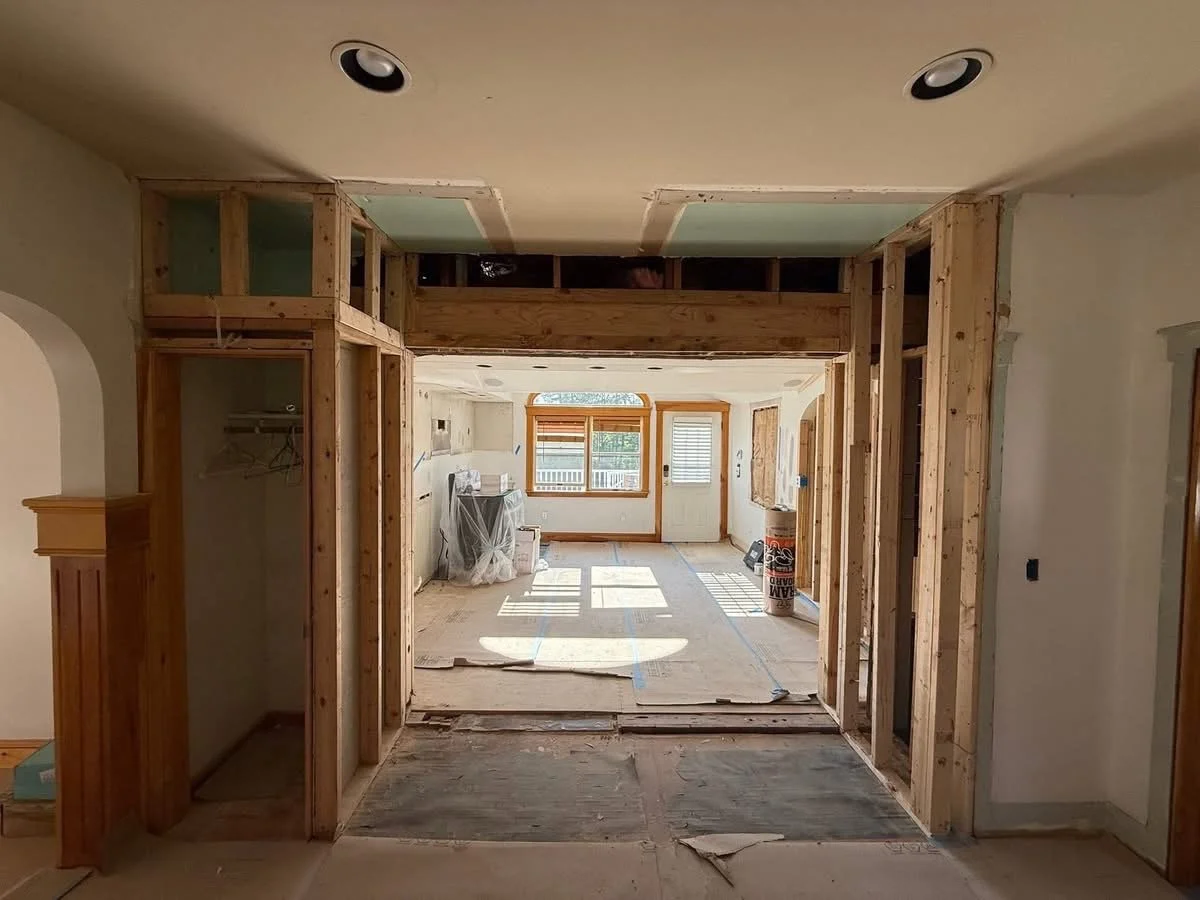 Interior of a house under renovation, showing unfinished framing and construction materials in the living area.