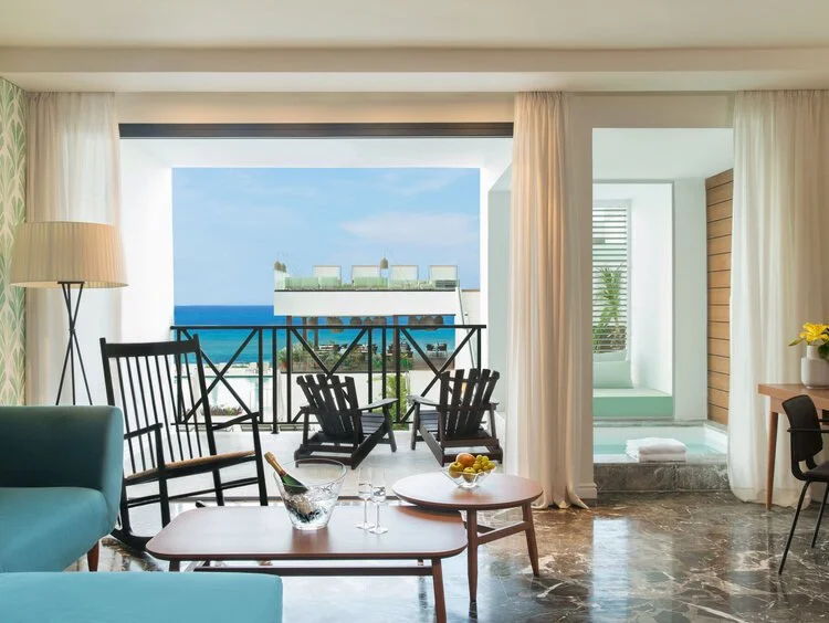 Living room with ocean view, balcony with chairs, and bathroom with bathtub.