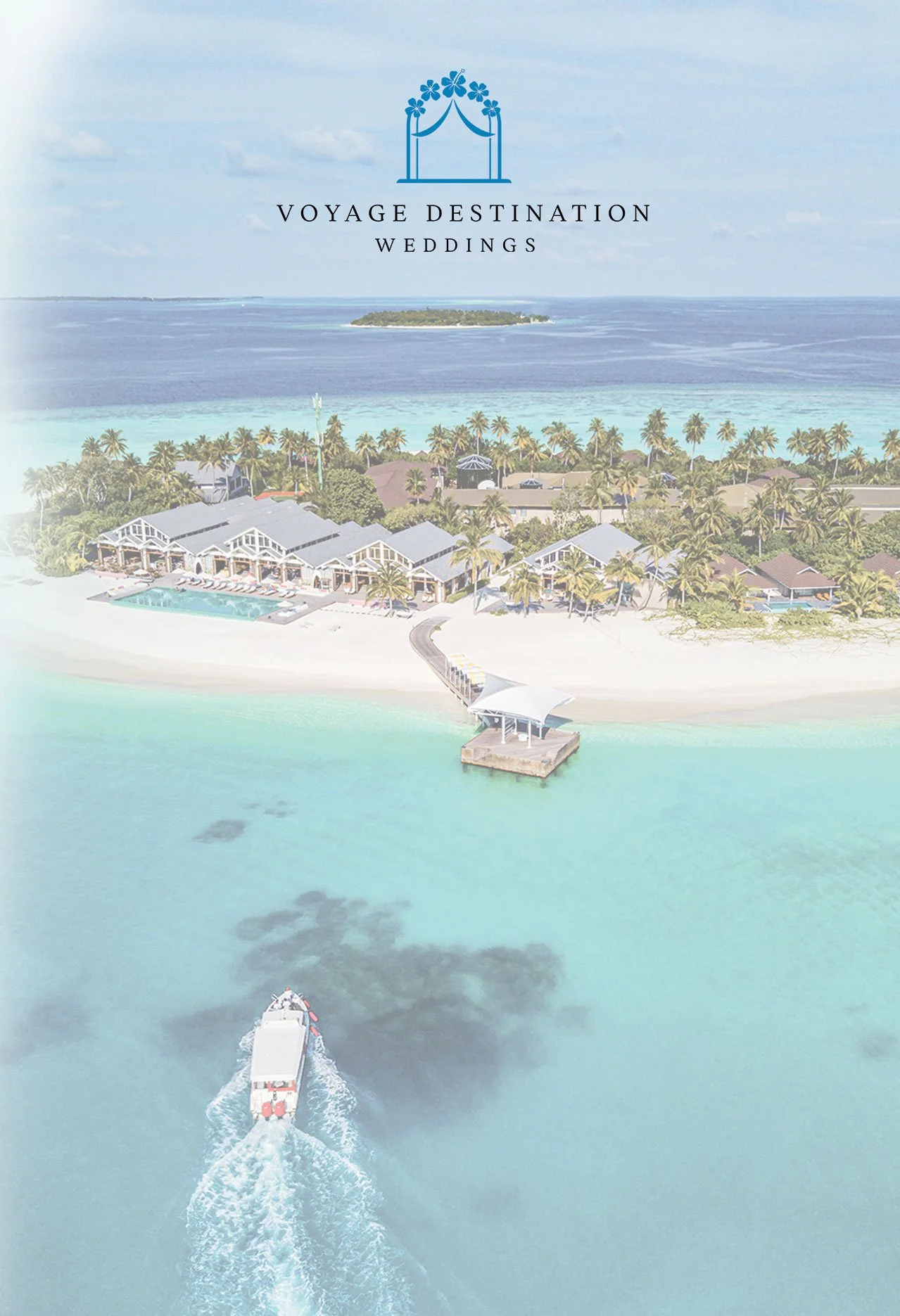 Aerial view of a tropical resort with a large building complex, pool, palm trees, and a pier extending over turquoise water, with a boat heading away from the island.