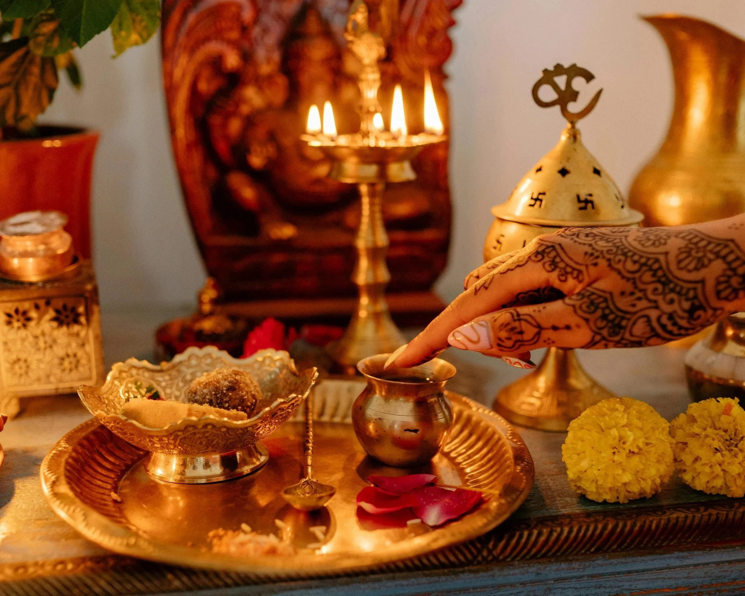 Traditional puja altar with lit oil lamps, flowers and henna – sacred blessing space at Spark Healing Toronto & Playa del Carmen