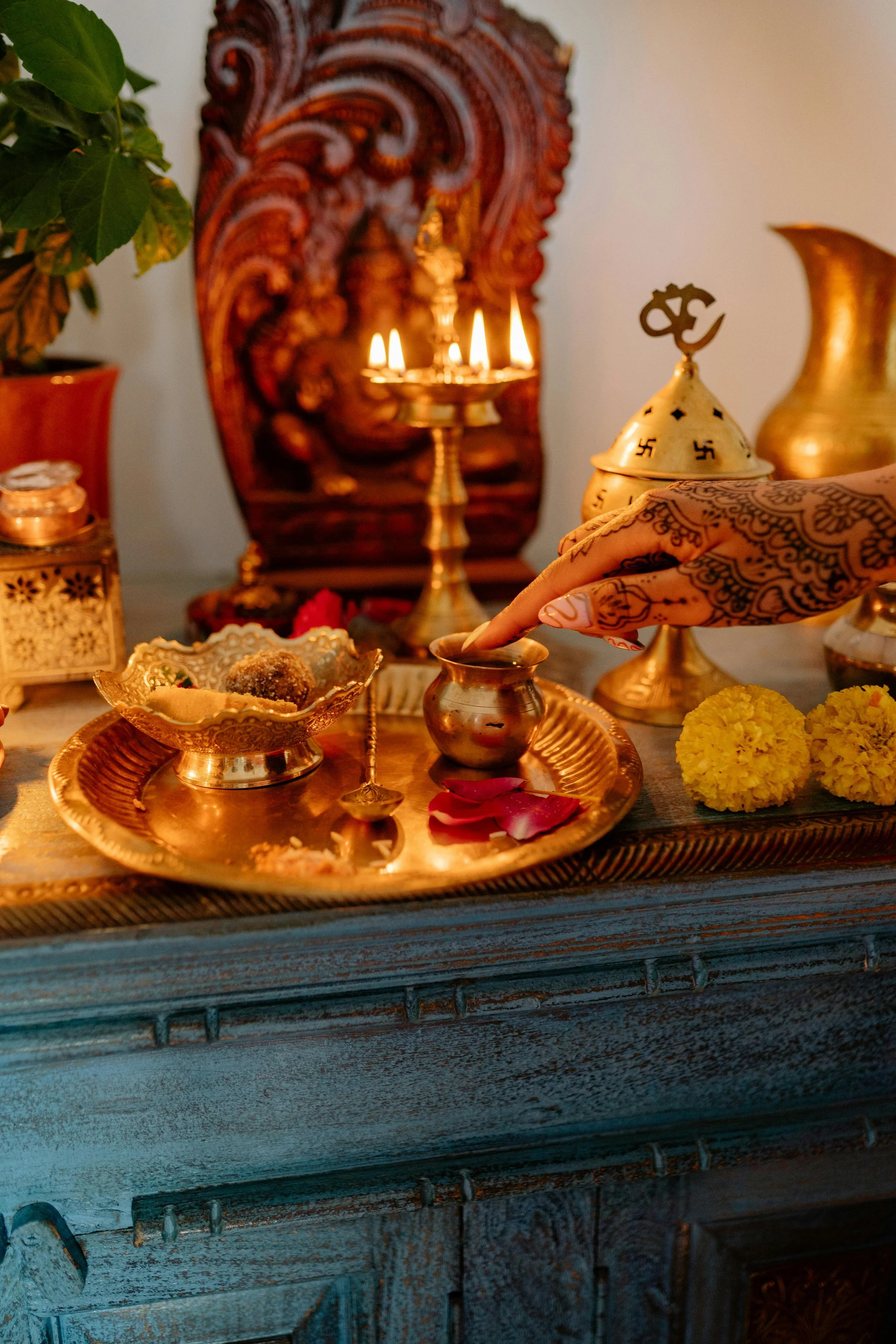 Traditional puja altar with lit oil lamps, flowers and henna – sacred blessing space at Spark Healing Toronto & Playa del Carmen