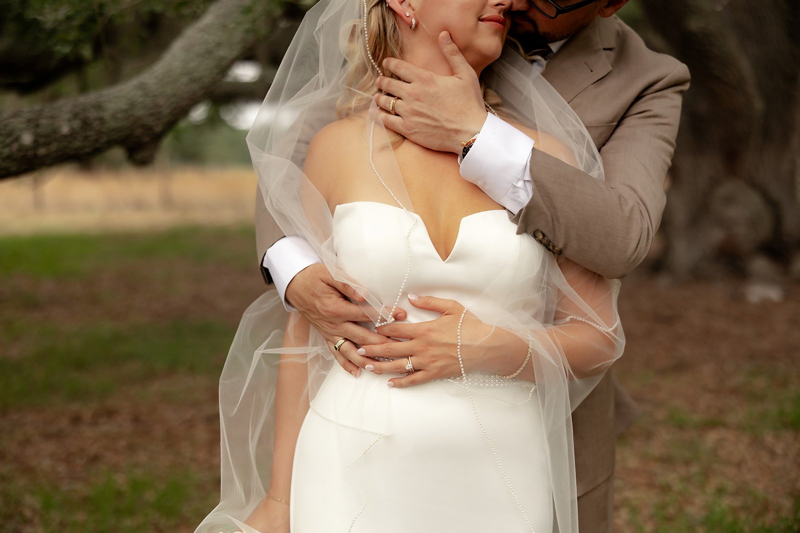 Close-up portrait of groom holding bride's face tenderly, wedding rings visible, at Browns Grove Sarasota