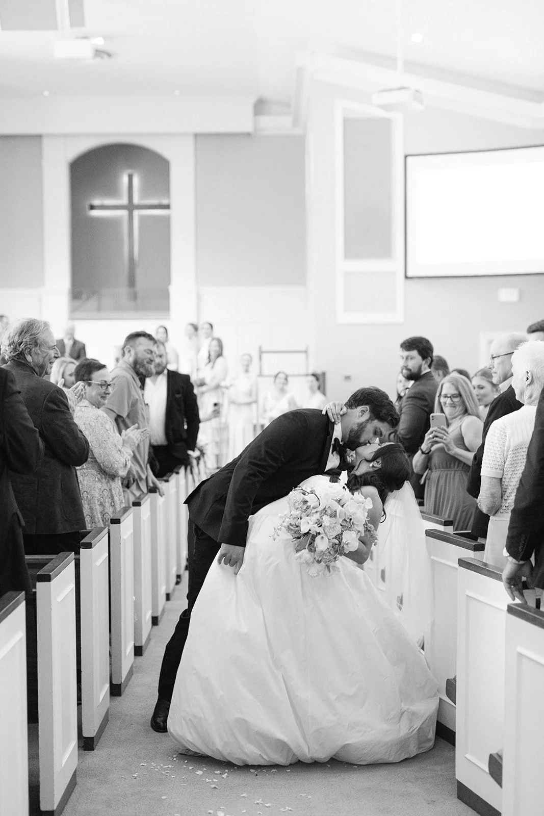 bride-groom-first-kiss-dip-church-aisle-ceremony-black-white-tampa-wedding.jpg