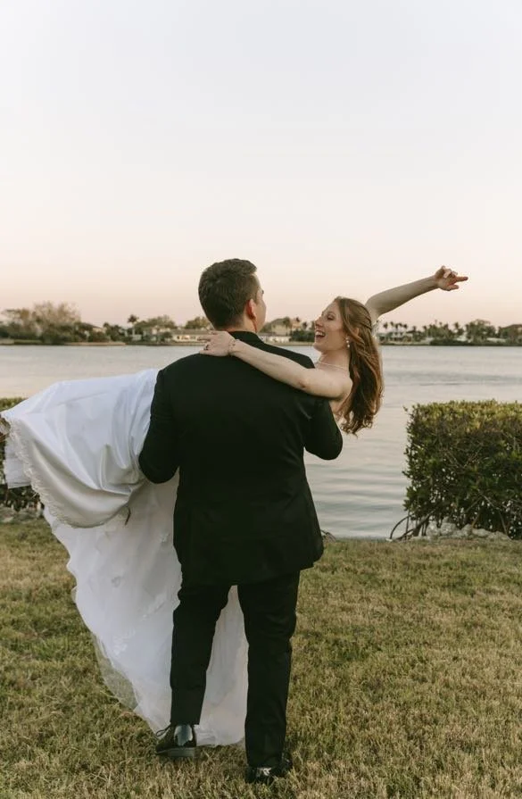 groom-lifting-bride-waterfront-golden-hour-sunset-wedding-planner-tampa.jpg