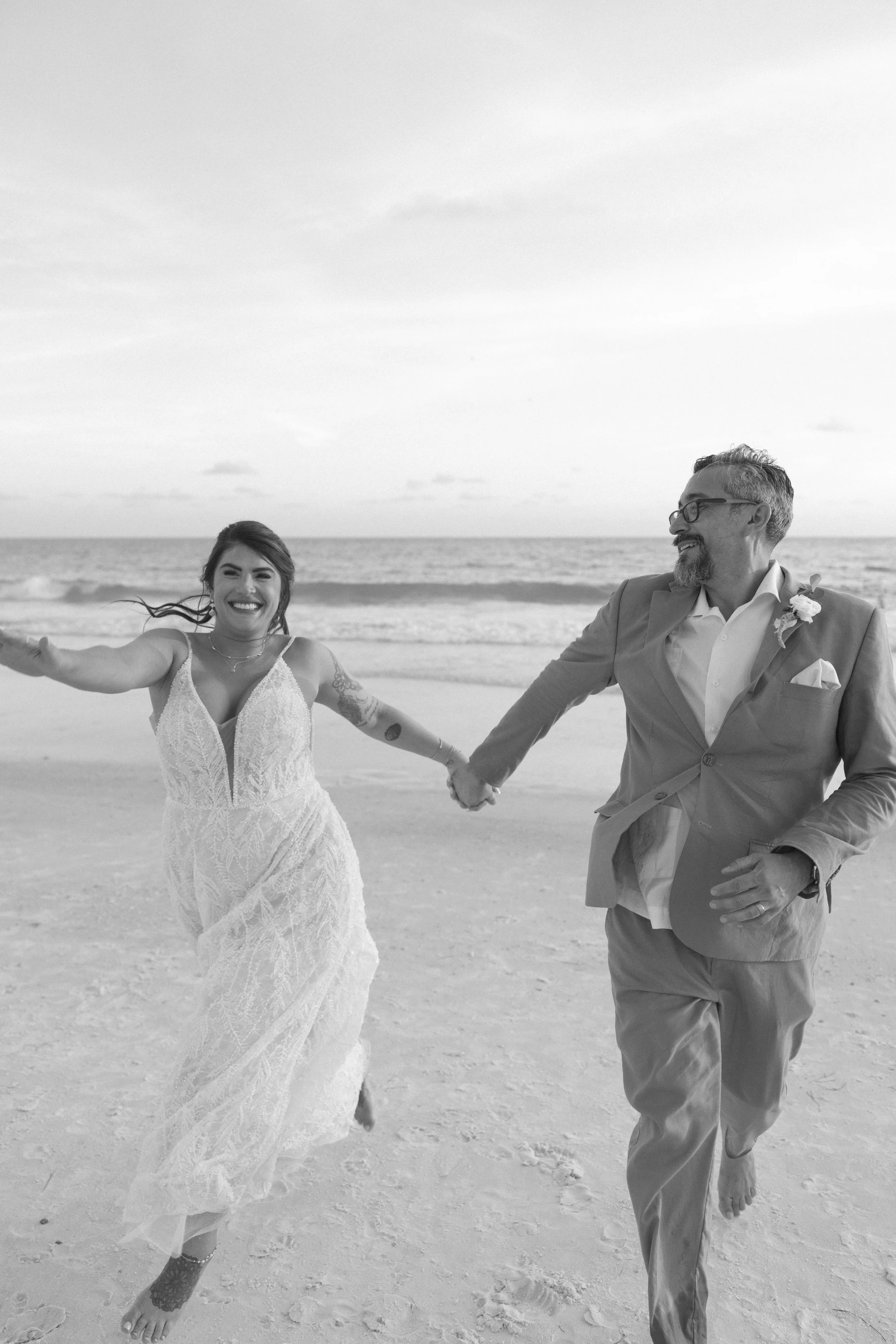 bride-groom-running-beach-black-and-white-grand-pavilion-sandbar-anna-maria-island-wedding.jpg
