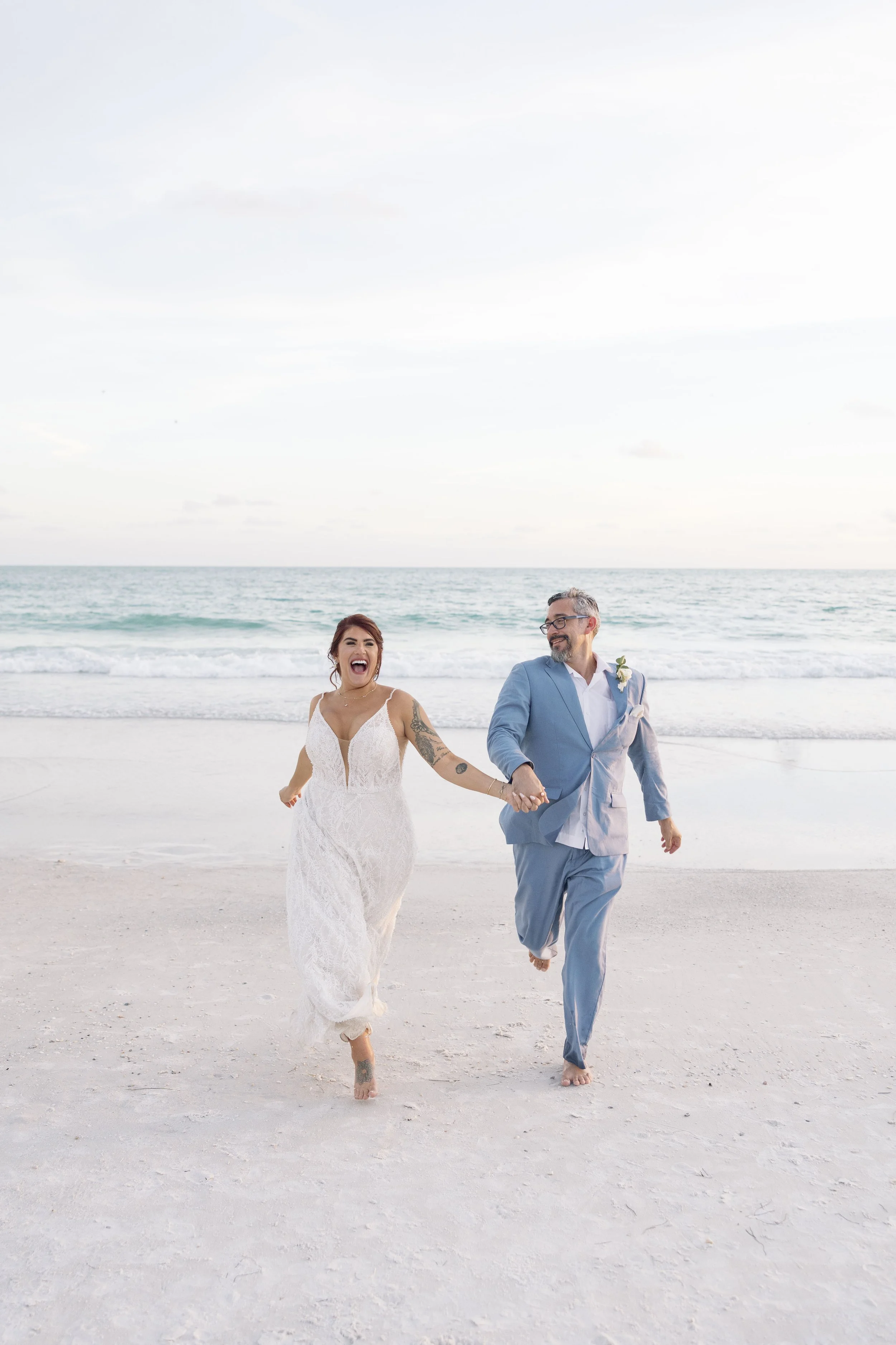 bride-groom-running-beach-laughing-grand-pavilion-sandbar-anna-maria-island-wedding.jpg