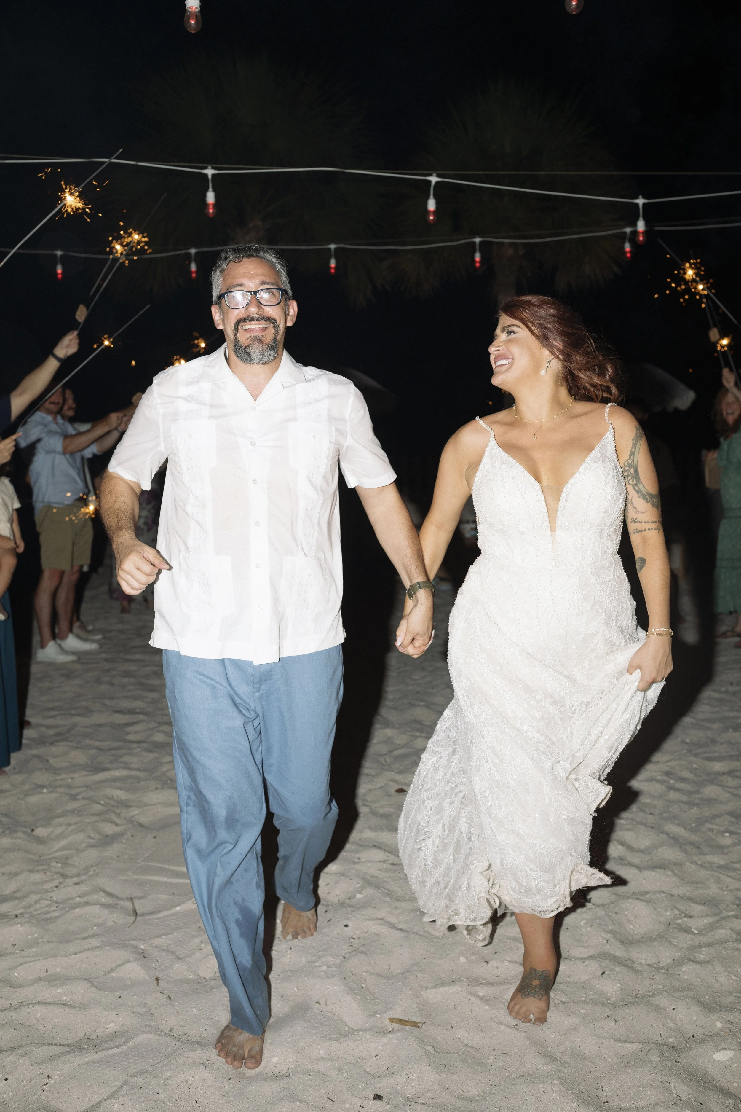 couple-walking-string-lights-reception-grand-pavilion-sandbar-wedding.jpg