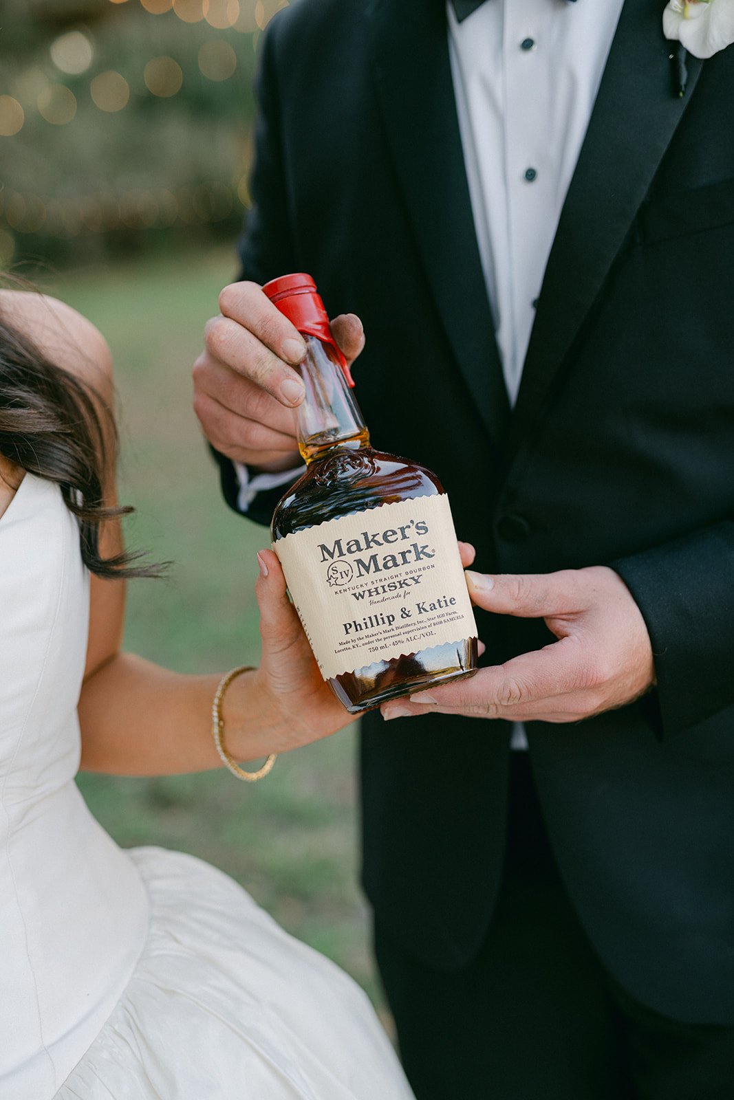 Bride and groom holding a custom Maker's Mark Kentucky Straight Bourbon bottle personalized with "Phillip & Katie" — a unique and personal wedding detail at their Tampa celebration