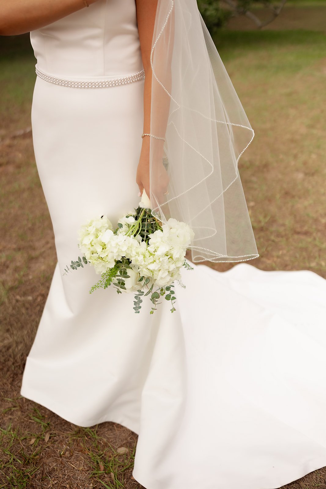 Detail shot of bride's dress train, white hydrangea bouquet, and pearl-edged veil at Browns Grove Sarasota