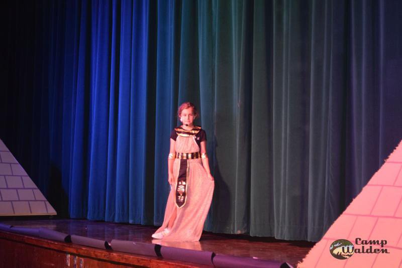 Child in Egyptian costume on stage with pyramids and curtains in the background
