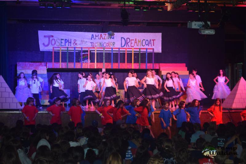 School production of "Joseph and the Amazing Technicolor Dreamcoat" on stage with performers in colorful costumes