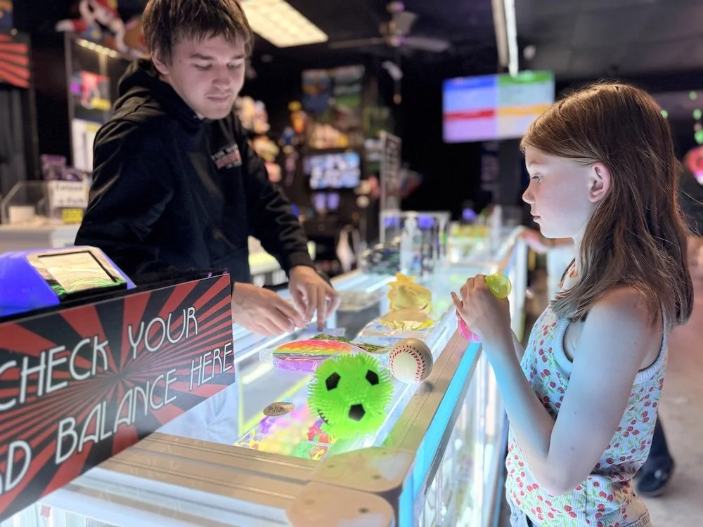 A girl using her tickets from an arcade to redeem a prize