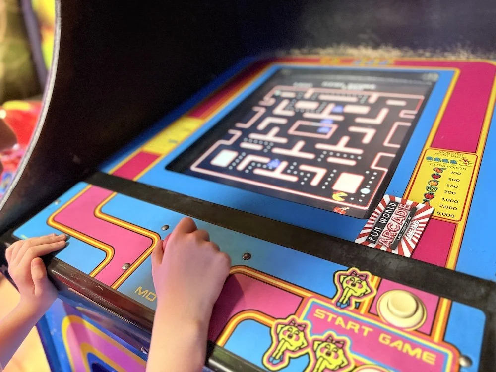 A high-quality image of someone playing Pac-Man on an arcade machine