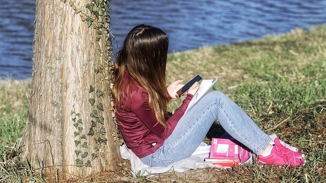 girl leaning on a tree journaling in nature