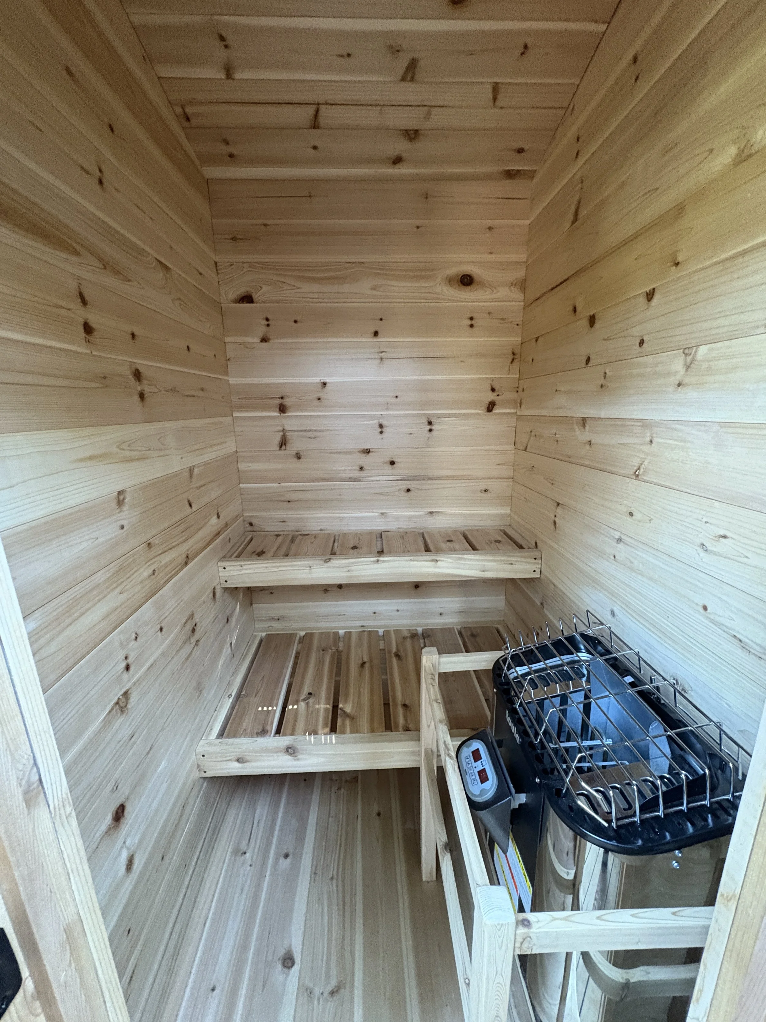 Interior of a wooden sauna room with benches and a heater.