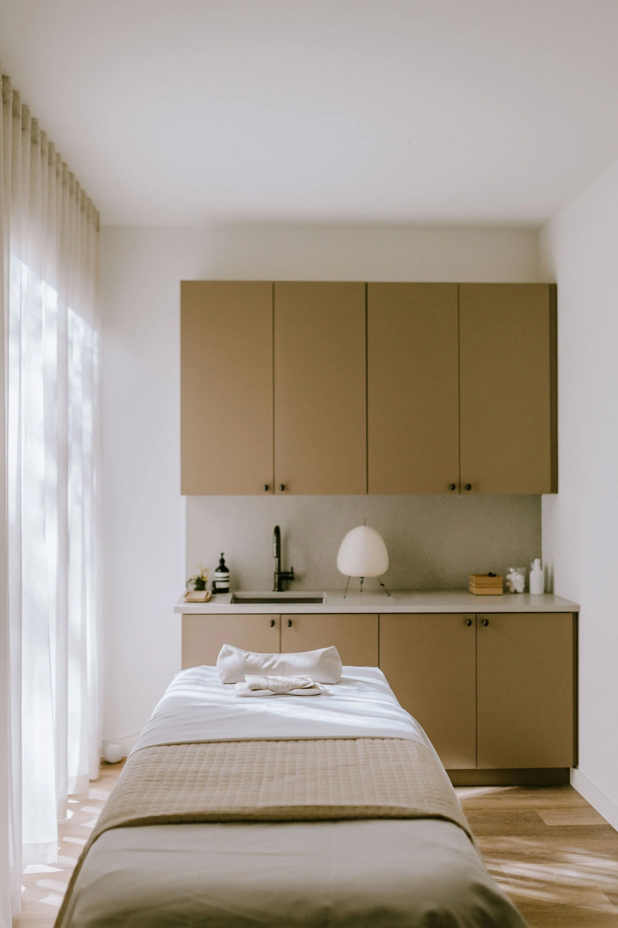 massage therapist room with window and cabinets and sink