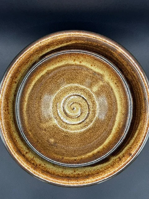 Top view of a brown ceramic bowl with a spiral design in the center