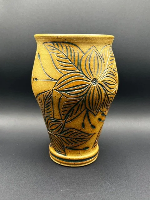 Yellow ceramic vase with black floral and leaf pattern.
