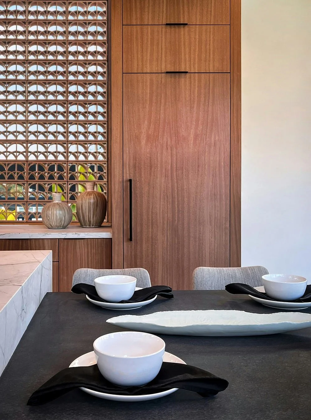 Warm terracotta breeze block divider wall in a minimalist dining space using Ispirare’s signature Split Loop ceramic tile.