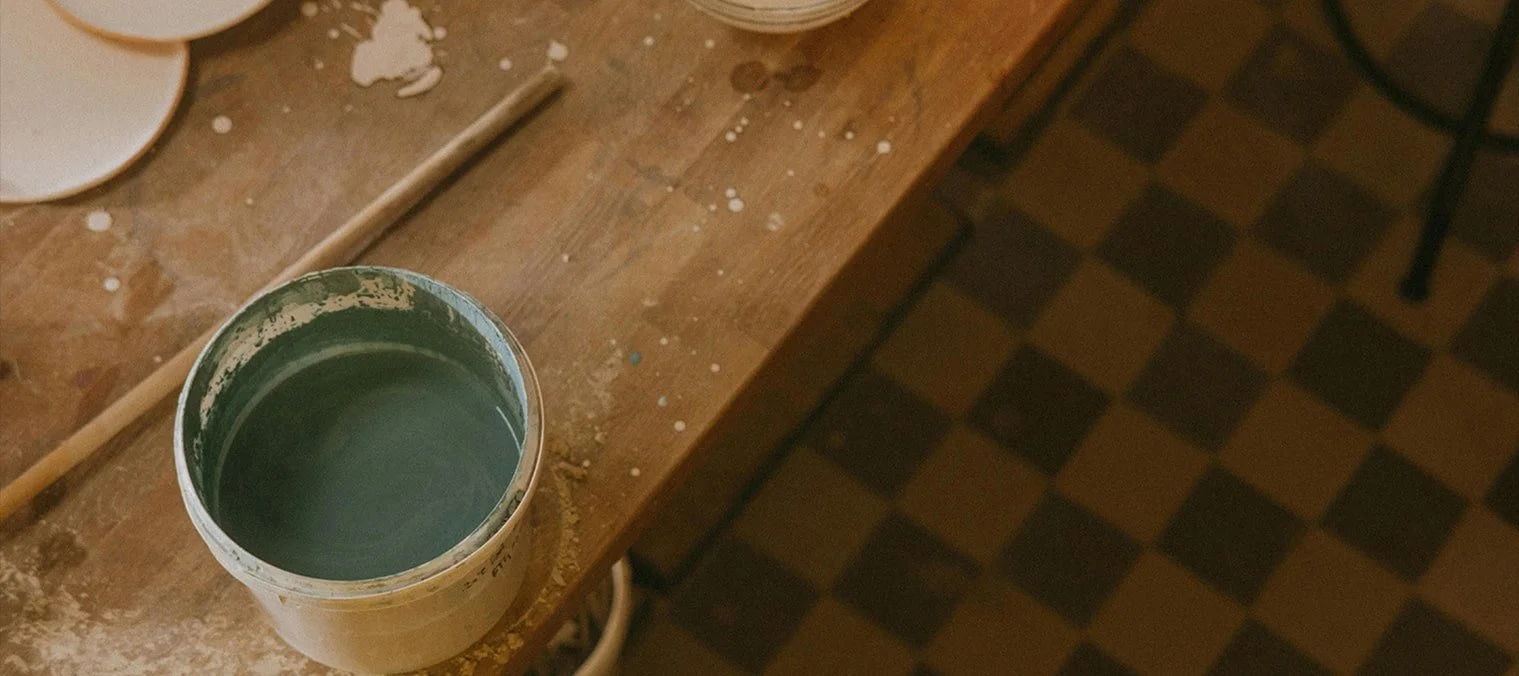 Hand-cut ceramic tiles on a work surface beside glazing materials
