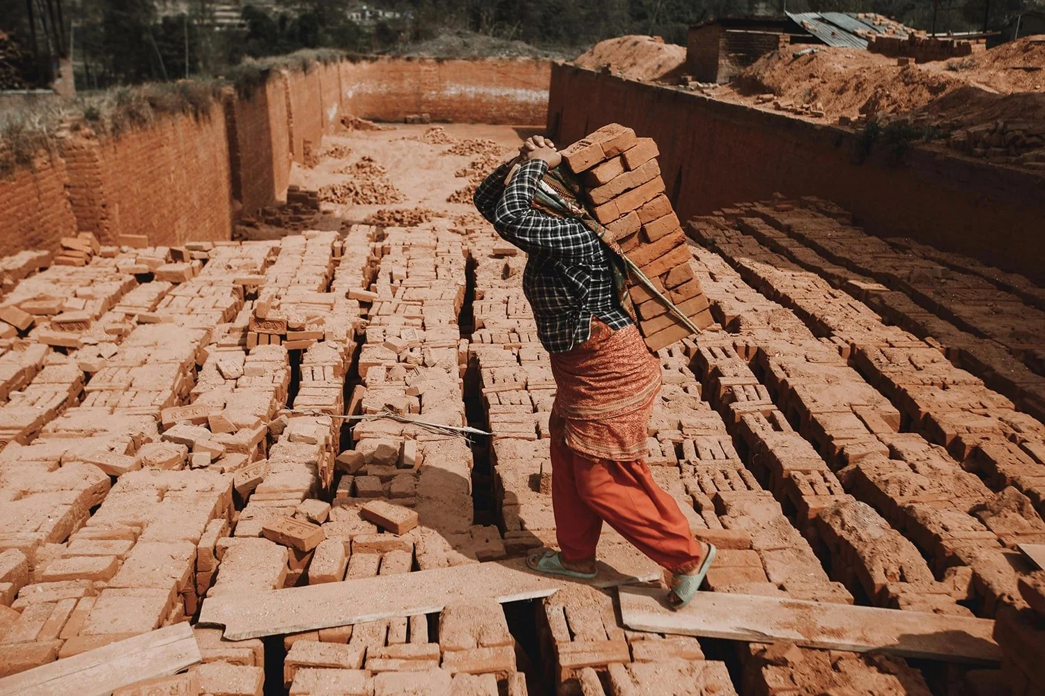 Rows of handmade terracotta tiles drying outdoors in a traditional kiln yard
