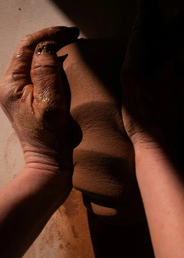 Close-up of hands shaping natural clay during ceramic tile production