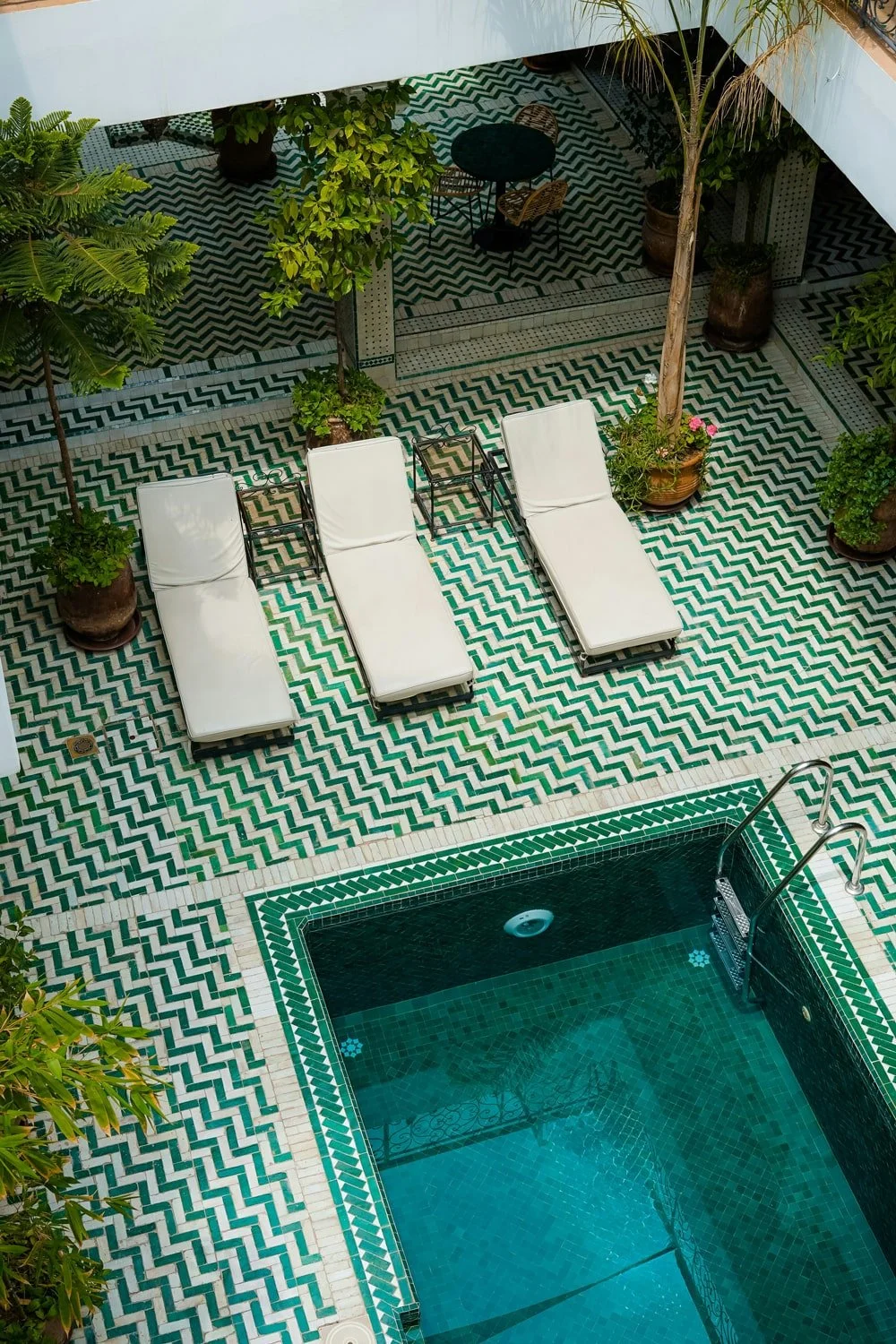 Geometric ceramic tile pattern surrounding a Mediterranean-style swimming pool