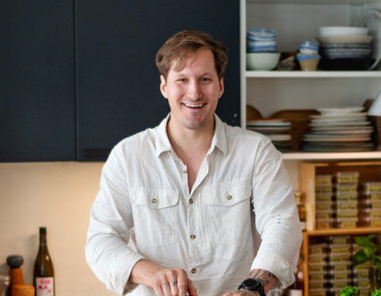 Man smiling and cooking in a modern kitchen, ren mat, økologisk. ravneberget, jørgen ravneberg, sanking, ville vekster, bærekraftig mat, norsk natur, sankebøker, sankeren og kokken, kurs i sanking