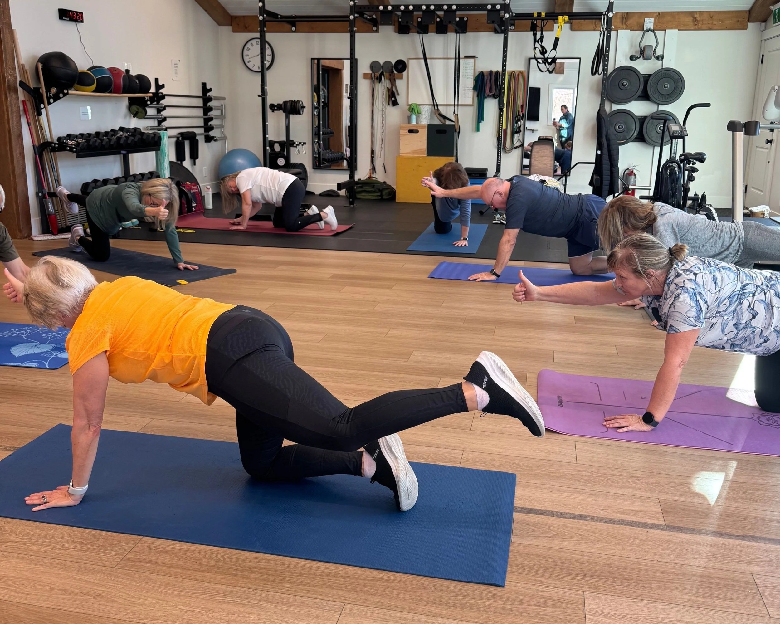 Group strength training class at Restorative Whole Health integrative health clinic in Okotoks, Alberta, showing diverse ages participating in physiotherapy-based movement exercises