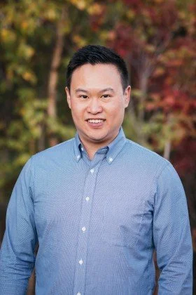 Portrait of a young man smiling outdoors with autumn trees in the background