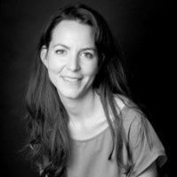 Black and white portrait of a woman with long hair, smiling, wearing a casual top.
