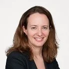 Portrait of a smiling woman with shoulder-length brown hair, wearing a dark blazer.