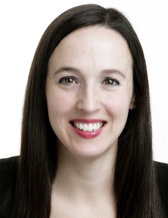 Close-up portrait of a young woman with long dark hair, smiling, against a white background.